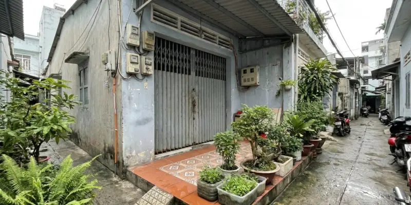 Căn nhà cấp bốn trong hẻm nhỏ tại thành phố với cổng sắt và đồng hồ điện gắn tường