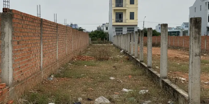 Ảnh bìa bài án phí tranh chấp đất đai: thửa đất trống ở ven đô Việt Nam có cọc mốc bê tông đánh dấu ranh giới giữa hai nhà