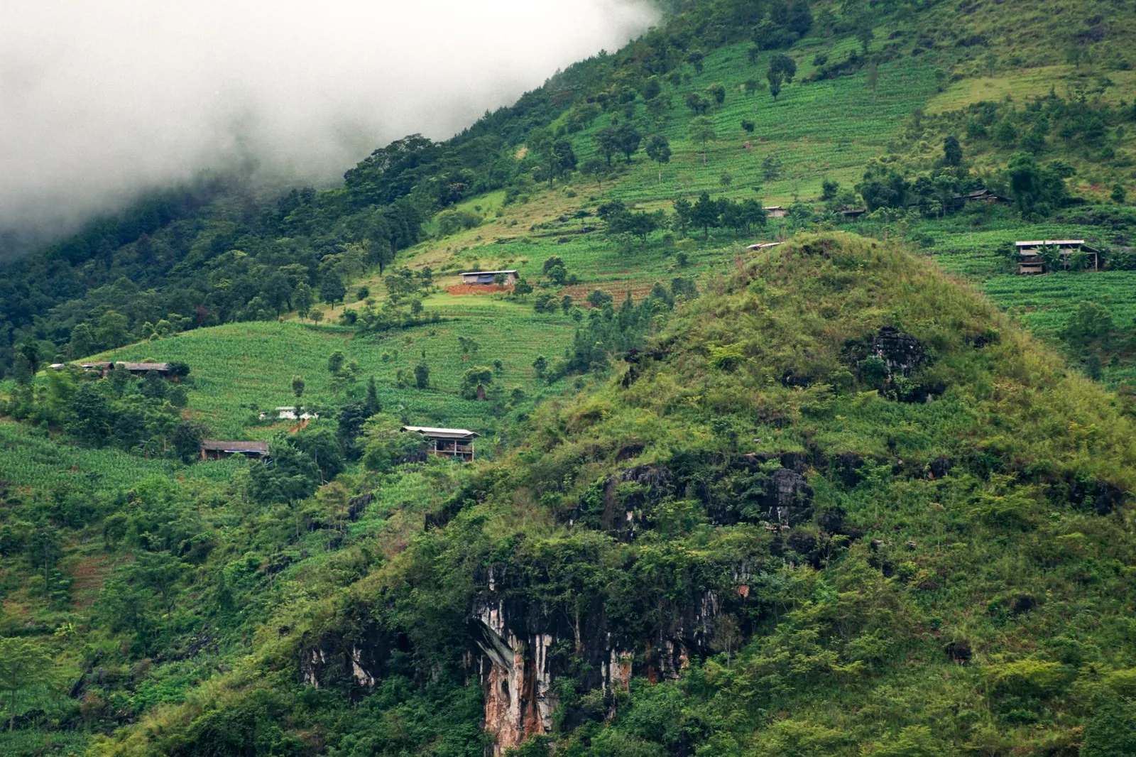 Sườn đồi ở Hà Giang, Việt Nam, xen lẫn ruộng nương và vài nếp nhà dân, minh họa câu hỏi đất rừng có lên đất ở được không
