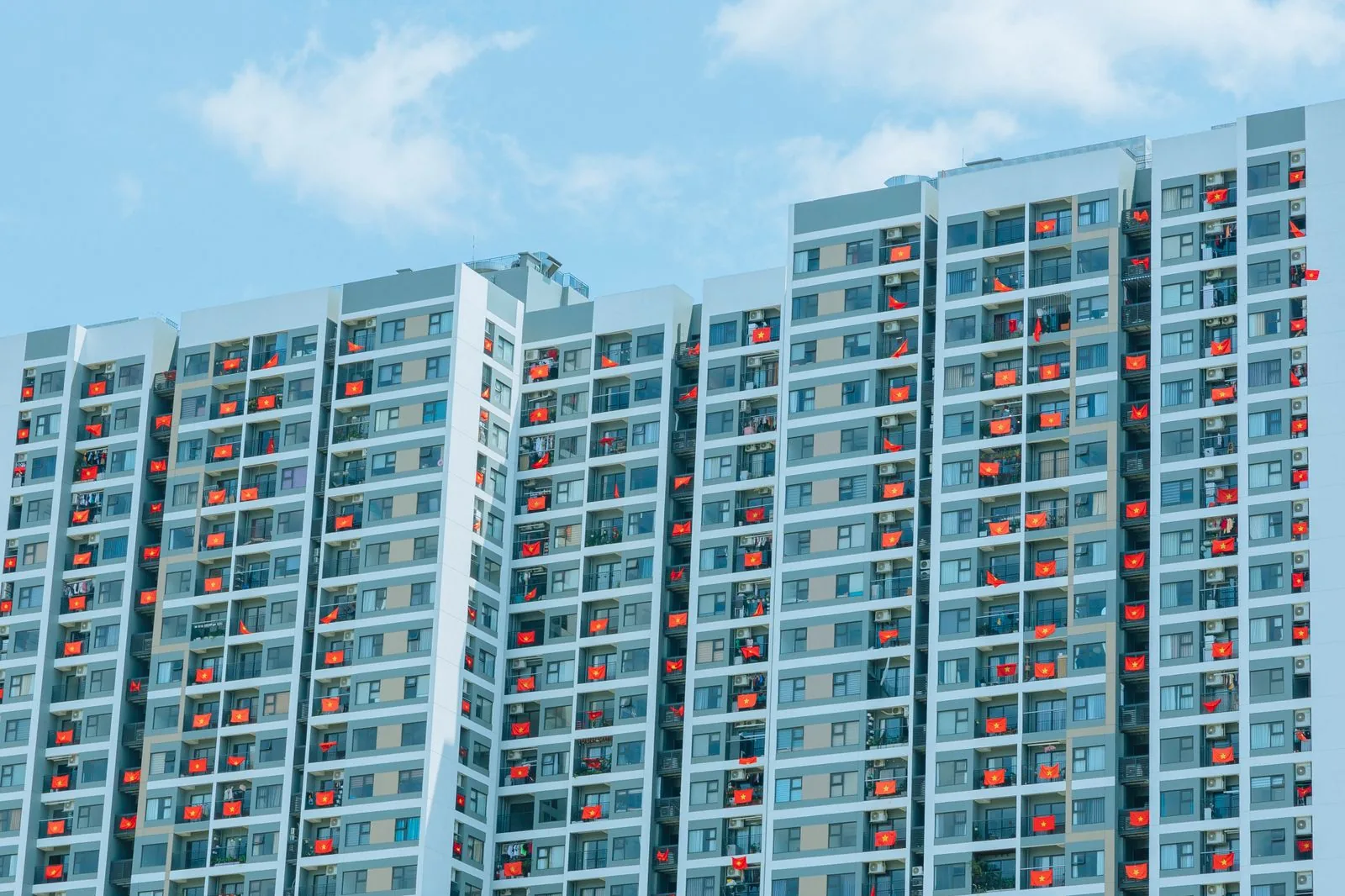 Tòa chung cư cao tầng ở Hà Nội, nhiều ban công treo cờ đỏ sao vàng, minh họa căn hộ thương mại có nhiều chủ sở hữu