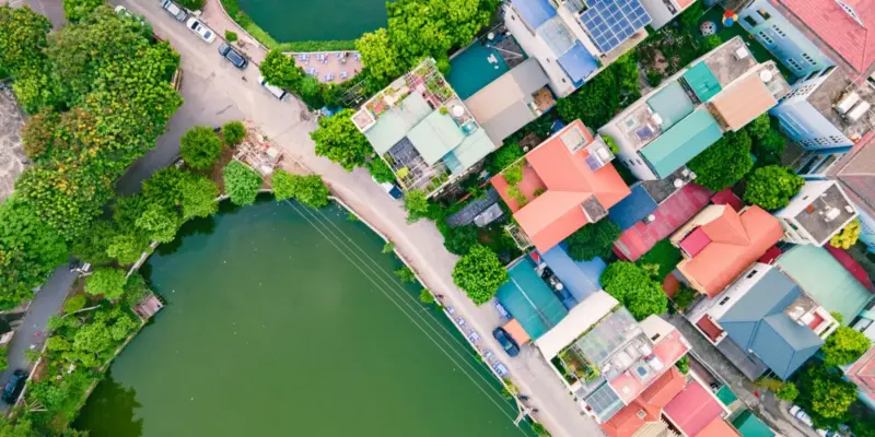 Ảnh bìa bài nộp thuế đất ở đâu: ảnh chụp từ trên cao một khu dân cư ở Hà Nội với những ngôi nhà nhiều tầng mái nhiều màu xen hồ nước và cây xanh, minh họa đất ở phải nộp thuế sử dụng đất phi nông nghiệp