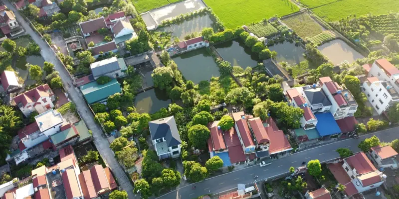 Ảnh bìa bài sổ đỏ hộ gia đình: ảnh chụp từ trên cao một làng quê Việt Nam với nhà mái ngói đỏ xen cây xanh, ao nước và ruộng lúa, minh họa đất ở của các hộ gia đình nông thôn