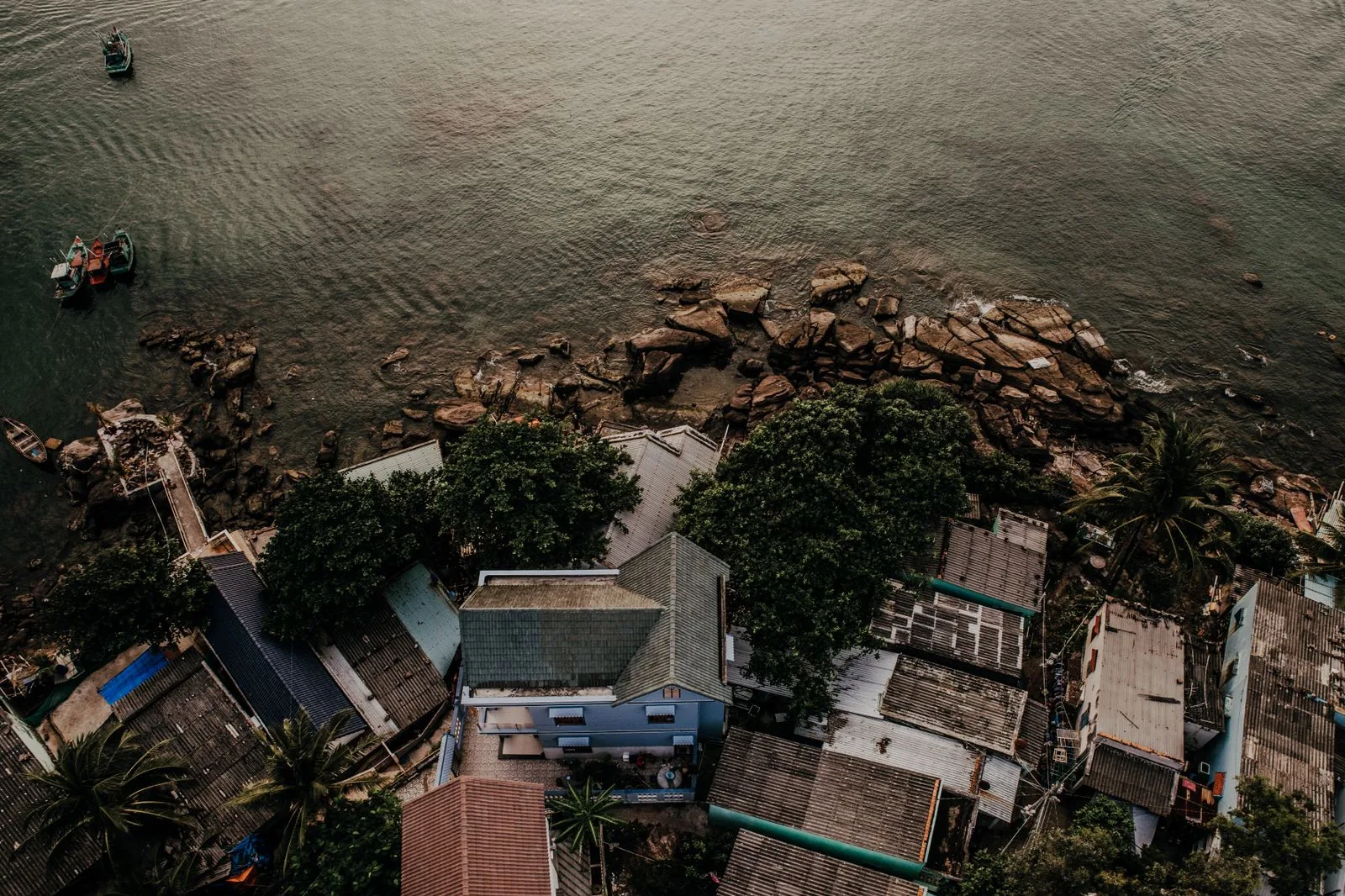 Làng ven biển ở Việt Nam nhìn từ trên cao, mái nhà sát mép đá và mặt nước, minh họa đất mua lại chỉ dùng phần thời hạn còn lại